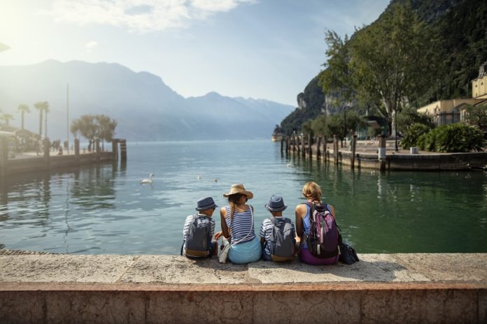 Family sitting in harbor of Riva del Garda and enjoying view of Lake Garda