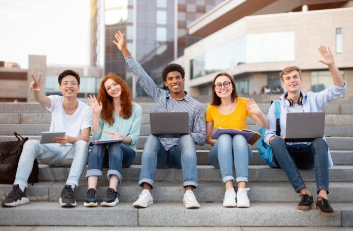 Multiracial students raising hands in the air and waving