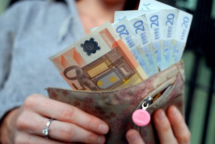 RAGAZZA DONNA CON PORTAFOGLIO SOLDI DENARO CONTANTE EURO BANCONOTE INFLAZIONE COSTO DELLA VITA