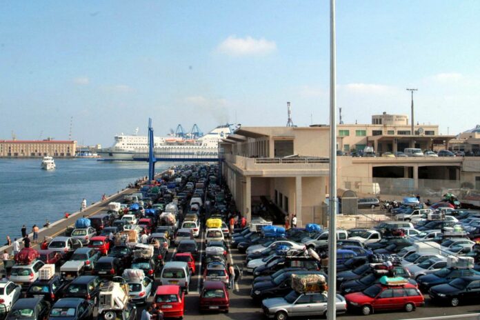 TURISTI SALGONO SUI TRAGHETTI PER LE VACANZE ESTIVE NAVE TRAGHETTO BANCHINA DEL PORTO PIENA DI AUTO E TURISTI