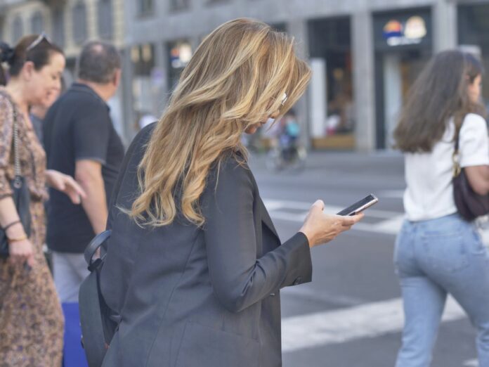 Telefono cellulare mezzo indispensabile nella vita quotidiana, molte persone in centro città tutte munite di smartphone o iphone