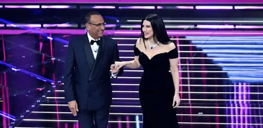 Sanremo 2026 al via con omaggio a Pippo Baudo, standing ovation per il ricordo di Vessicchio. Can Yaman fa cantare Laura Pausini in turco