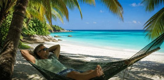Tutti online e sempre più stanchi: il digital detox è il nuovo lusso dell’estate 2026 uomo rilassato su amaca in spiaggia