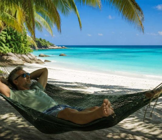 Tutti online e sempre più stanchi: il digital detox è il nuovo lusso dell’estate 2026 uomo rilassato su amaca in spiaggia