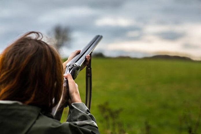 Girl with a shotgun skeet shooting.